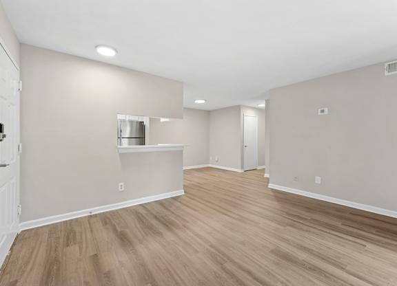 A room with light wood flooring and white walls.