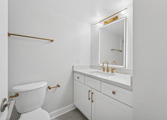 A white bathroom with a toilet, sink and mirror  at Riverside Apartments, Alexandria, Virginia