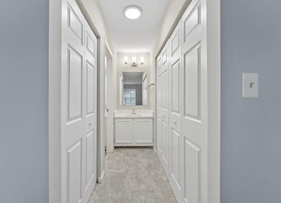 A long hallway with white doors and a light switch on the wall.