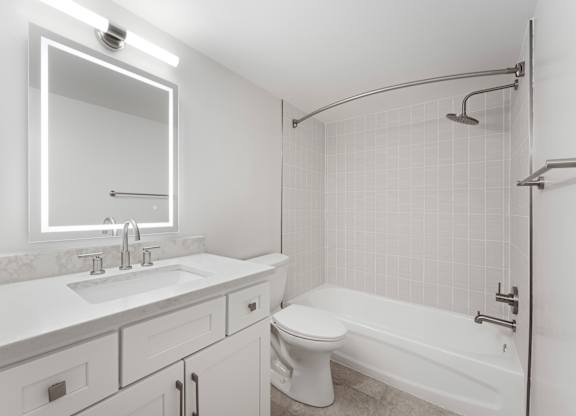 A white bathroom with a sink, mirror, toilet and bathtub.