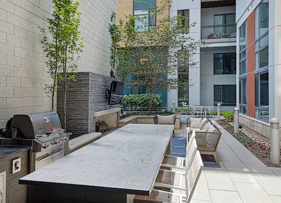 A patio with a grill and a table surrounded by buildings.