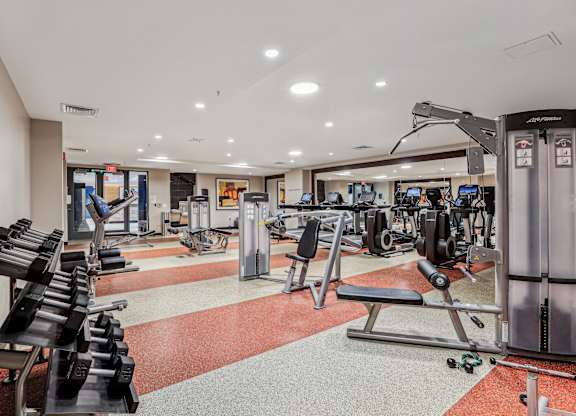 A gym with a variety of equipment including treadmills, weights, and exercise machines at The Maxwell Apartments, Arlington
