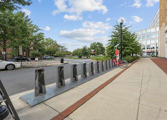 A row of bicycle racks are lined up on a sidewalk.