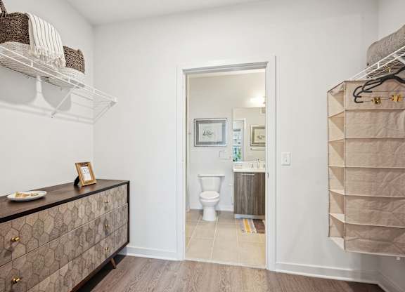 A bathroom with a toilet and a cabinet with a picture frame on top.