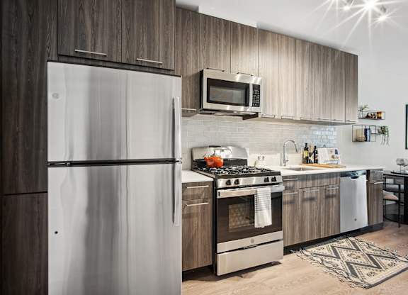 A modern kitchen with a refrigerator, oven, and microwave.