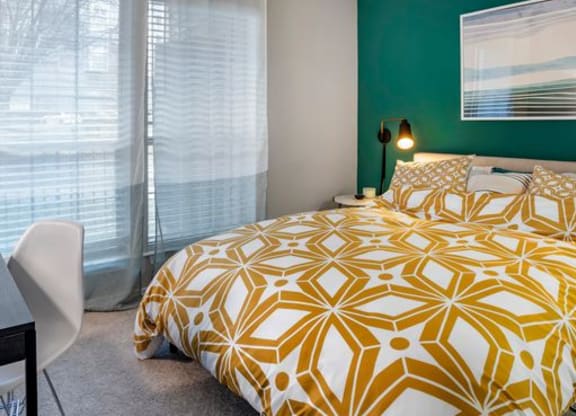 Bedroom with a green wall and a yellow and white bedspread at Elme Alexandria, Alexandria