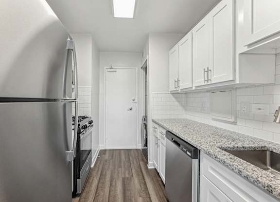 A kitchen with a stainless steel refrigerator and a granite countertop.
