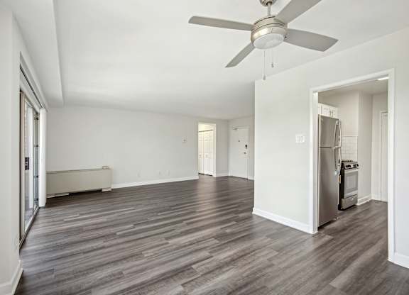 A room with a ceiling fan and wood flooring.