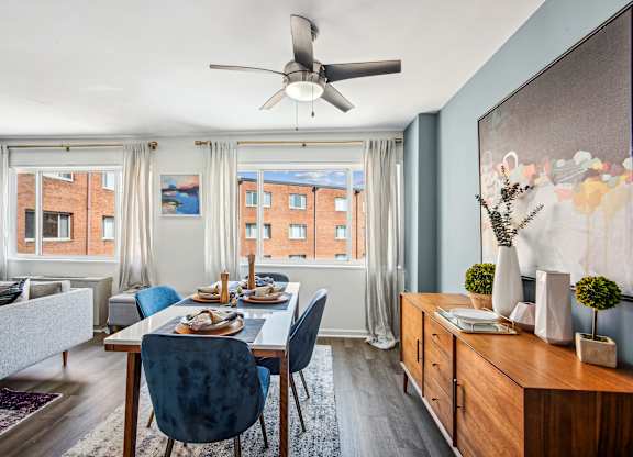 A dining room with a table set for four and a couch.