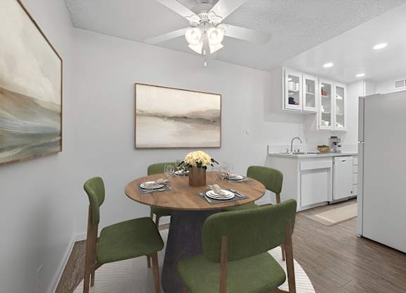 Kitchen 1005 Via Zapata apartment home with wood-style plank flooring, white cabinetry, white appliances and dining nook with overhead ceiling fan.