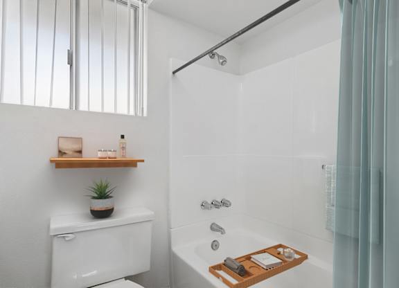 A white toilet with a wooden shelf above it in a bathroom.