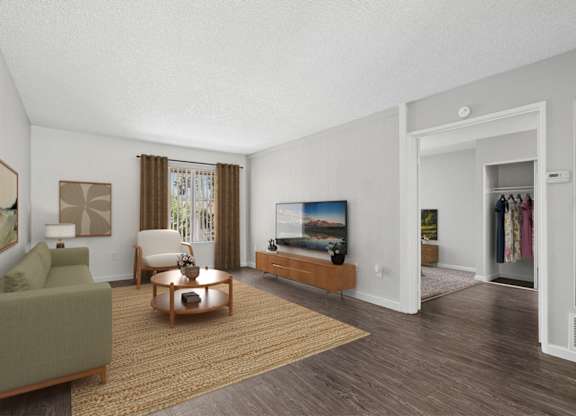 Spacious and charming living area in 955 Via Zapata apartment home with wood-style plank flooring, large windows and decorative wood paneled accent wall painted a light taupe/gray.