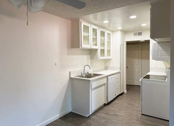 Kitchen 1005 Via Zapata apartment home with wood-style plank flooring, white cabinetry, white appliances and dining nook with overhead ceiling fan.