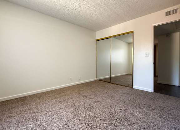 First bedroom in 1005 Via Zapata apartment home with plush carpeted flooring, large window and spacious closet.