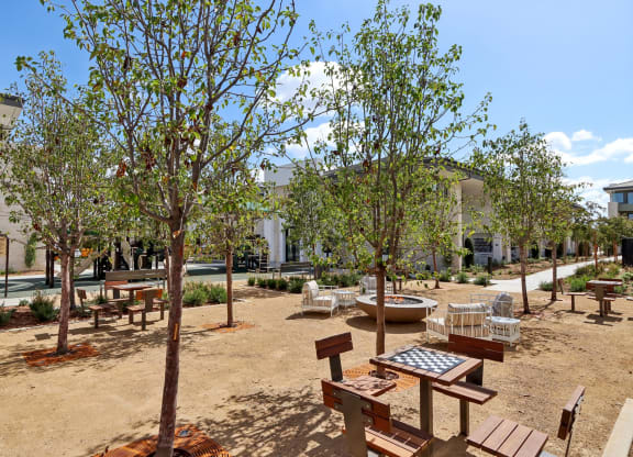 a courtyard with benches and trees and a building in the background at The Max on Jefferson Apartments, California, 92562