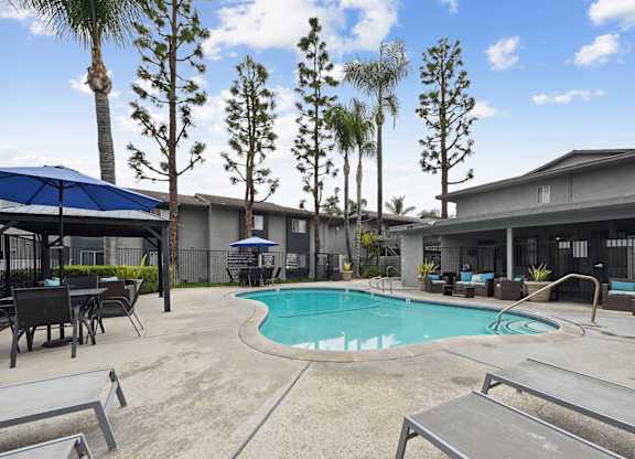 A pool surrounded by palm trees and lounge chairs.