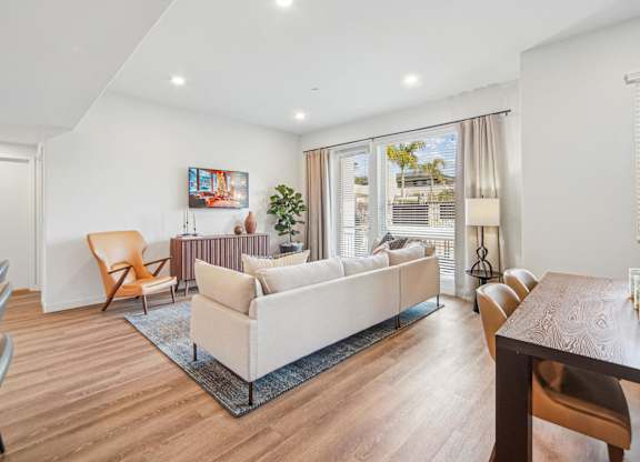 A living room with a white couch and a wooden table. at The Max on Jefferson Apartments, Murrieta, California
