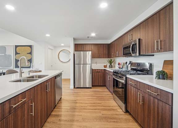 A modern kitchen with wooden cabinets and stainless steel appliances. at The Max on Jefferson Apartments, California, 92562