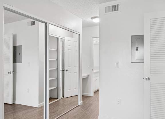 Hallway in bedroom leading to private bathroom. Hallway is lined with mirrored closet doors allowing for plenty of storage space. The mirrors make the space feel even bigger and reflect the lighting from the windows, which gives a warm and welcoming feeling to the space.