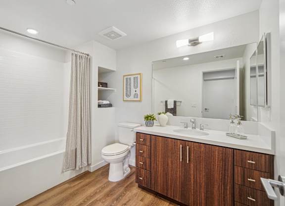 A bathroom with a toilet, sink, and mirror. at The Max on Jefferson Apartments, California