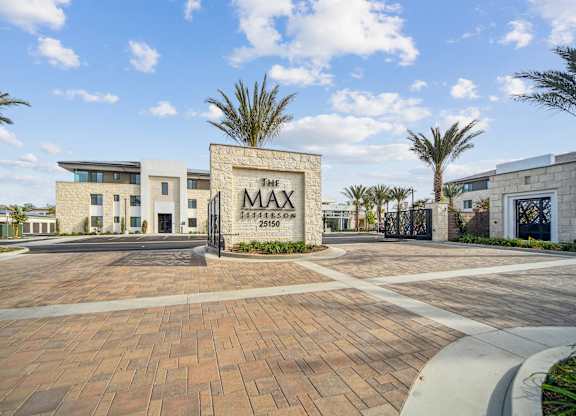The image shows a modern building with a sign that reads  at The Max on Jefferson Apartments, Murrieta, CA