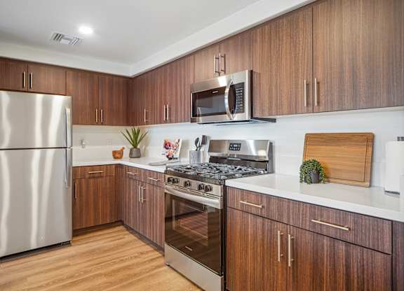 A modern kitchen with wooden cabinets and stainless steel appliances. at The Max on Jefferson Apartments, Murrieta, 92562