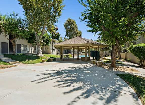 A tree-lined driveway leads to a covered patio area.