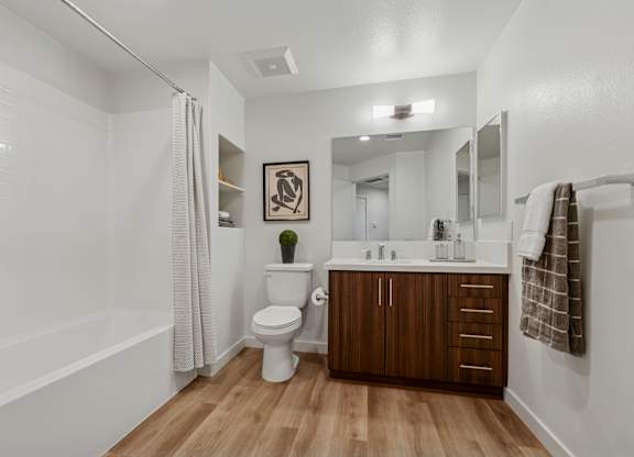 Bathroom in The Park 2-bedroom apartment with heathered plank flooring, quartz countertops and a shower/tub.