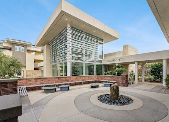 Peaceful courtyard outside The Park leasing office with unique stone fountain and bench seating.