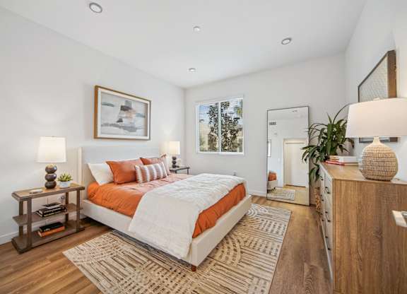 A bedroom with a large bed and a wooden nightstand at The Max on Jefferson Apartments, Murrieta, California