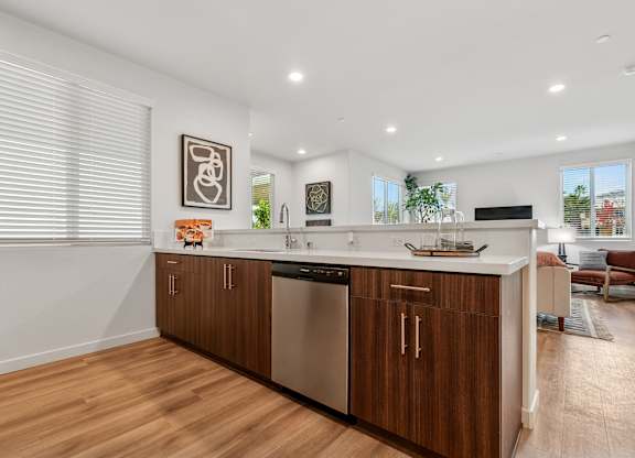 modern kitchen with wooden cabinets and stainless steel appliances, overlooking the living area in the Park 2-bedroom apartment home.