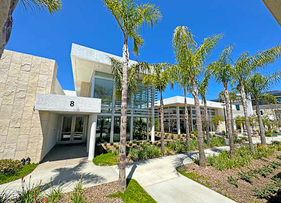 A modern building with a glass facade and palm trees in front.