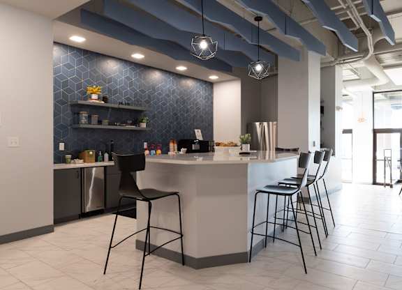 a kitchen with a counter and chairs in a lobby at The Residences at Tesson Ridge, Saint Louis, MO, 63128
