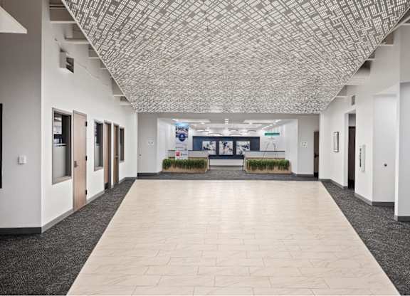 an empty hallway in a building with white walls and tiled floors at The Residences at Tesson Ridge, Saint Louis, 63128