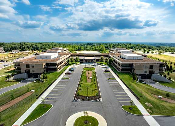 A large, modern building complex with a parking lot in front.