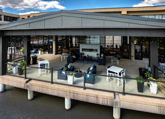 A patio with chairs and tables overlooking a body of water.