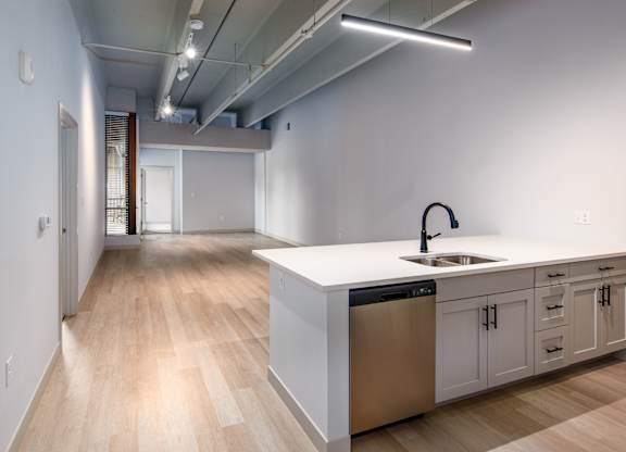 A modern kitchen with a white countertop and stainless steel appliances.