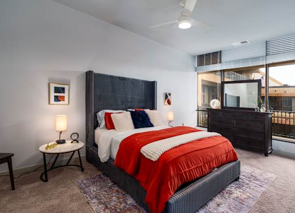 A bedroom with a large bed and a window overlooking a balcony.