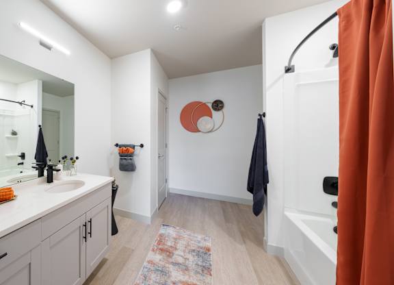 A bathroom with a white sink and orange shower curtain.