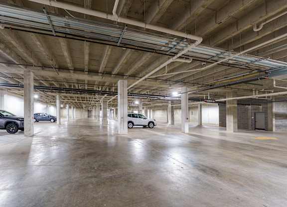 A spacious parking garage with concrete floors and multiple cars parked.