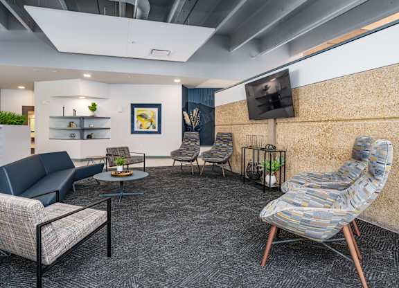 A modern living room with a grey carpet and a stone patterned chair.