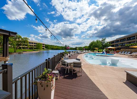A pool area with a hot tub and a view of a river.