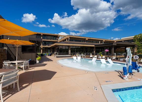 A sunny day at the pool with chairs and umbrellas.
