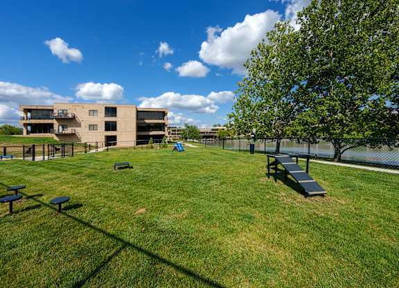 A grassy field with picnic tables and a building in the background.