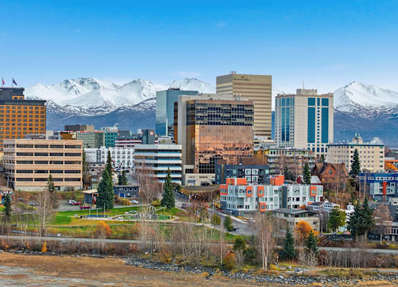 A cityscape with buildings and snow-capped mountains in the background.