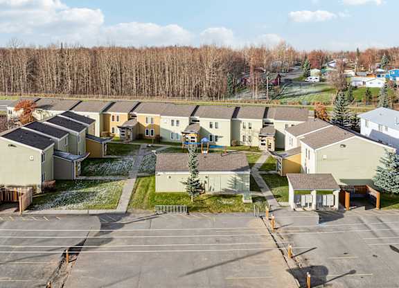 A parking lot in front of a building surrounded by trees.