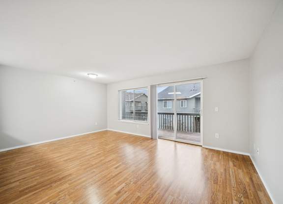 A room with wooden flooring and a window overlooking a balcony.