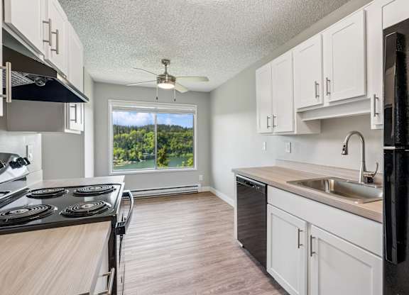 A kitchen with black appliances and white cabinets.