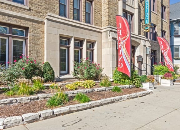 a sidewalk in front of a building with red flags