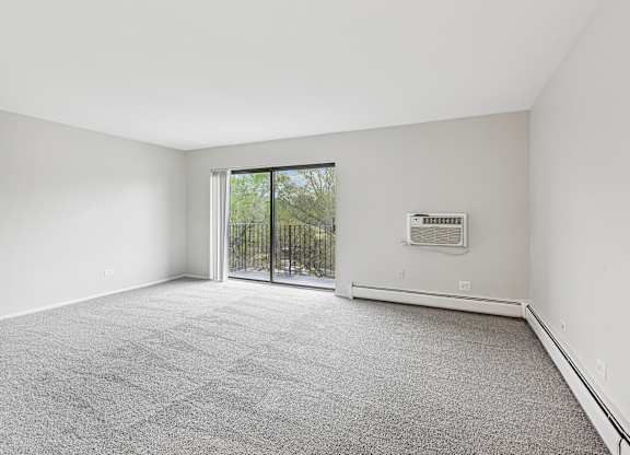 A room with a grey carpet and a sliding glass door.